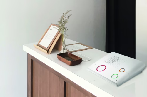 Das digitale Hausnotrufgerät GX-8 von Climax ist eine All-in-One-Alarmlösung. Im Bild steht es auf einer Kommode, daneben eine Schlüssel mit Kleingeld und ein Klemmbrett mit einem Blatt Papier dran.